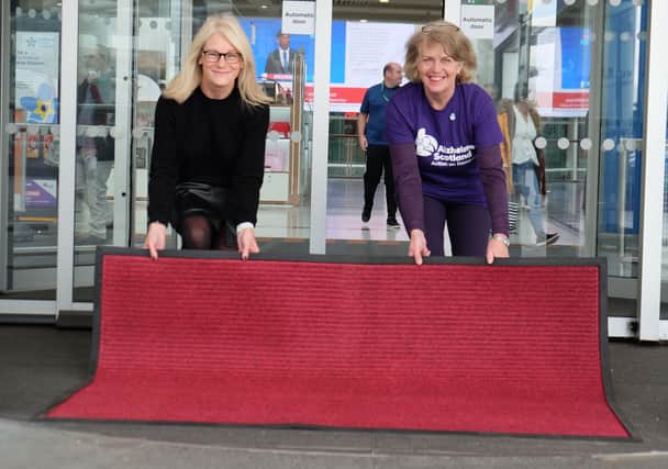 Braehead’s Lydia Brown and Anne McWhinnie, from Alzheimer Scotland, laying out a replacement red entrance mat at the mall.