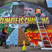 Artists paint a mural on a a wall next to the Clydeside Expressway near Scottish Events Centre  ahead of COP26 (Picture: Getty Images)