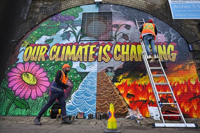 Artists paint a mural on a a wall next to the Clydeside Expressway near Scottish Events Centre  ahead of COP26 (Picture: Getty Images)