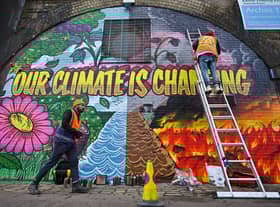 Artists paint a mural on a a wall next to the Clydeside Expressway near Scottish Events Centre  ahead of COP26 (Picture: Getty Images)