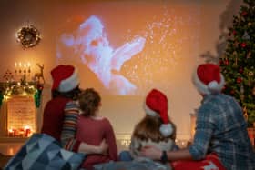 People having fun near tree indoors. Loving family watching holiday movies at home. Mother, father and daughters spending time together.