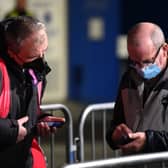 A supporter has his Covid-19 status checked as he arrives ahead of the English Premier League football match between Brighton and Hove Albion and Wolverhampton Wanderers at the American Express Community Stadium. (Photo by GLYN KIRK/AFP via Getty Images)