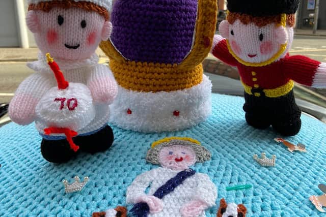 A post box in Glasgow with a knitted Queen’s guard, baker, crown, and The Queen with her corgis