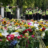 Police officers arrive at the gates of Balmoral in Scotland where flowers and tributes have been laid by members of the public following the death of Queen Elizabeth II. The Queen's coffin will be transported on a six-hour journey from Balmoral to the Palace of Holyroodhouse in Edinburgh, where it will lie at rest. Picture date: Sunday September 11, 2022.