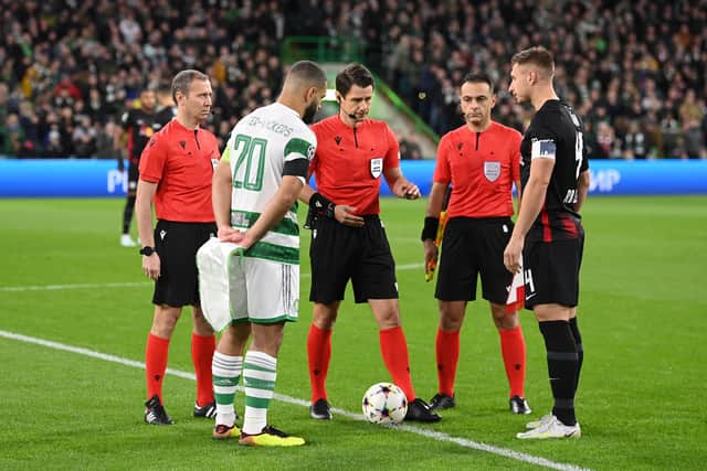 Referee Halil Umut Meler tosses the coin as the two captains look on before the UEFA Champions League group F match between Celtic and RB Leipzig at Celtic Park 