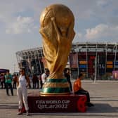 People pose for photos next to a giant replica on the World Cup trophy in front of Stadium 974 on November 18, 2022 in Doha, Qatar