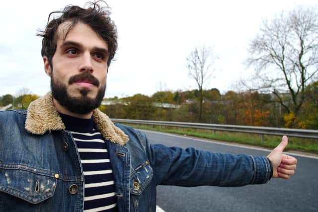 The film director at the side of a road in the UK - holding his thumb out waiting for a lift.