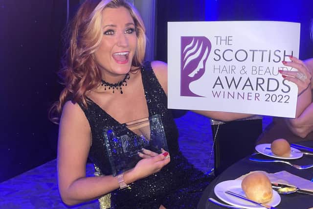The owner of Salon No 1 holds up the award for best in Glasgow