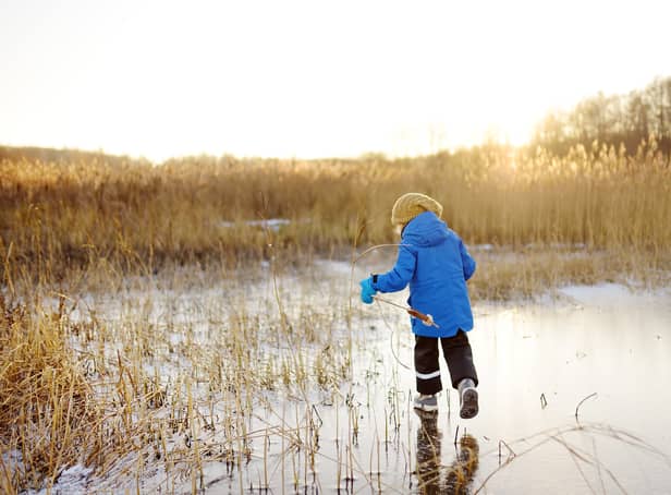 <p>Preschool boy is playing on the ice of a frozen lake or river on a cold sunny winter sunset. Child sliding and having fun with during family hiking. Kids outdoor games in winter</p>