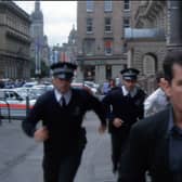 A screengrab from the movie Obit, featuring Charlie Sheen running with Police down St Vincent Place