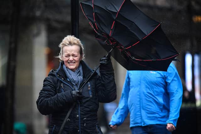 A woman battles to keep control of her umbrella in stormy weather.