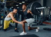Man with his trainer in gym (Adobe)