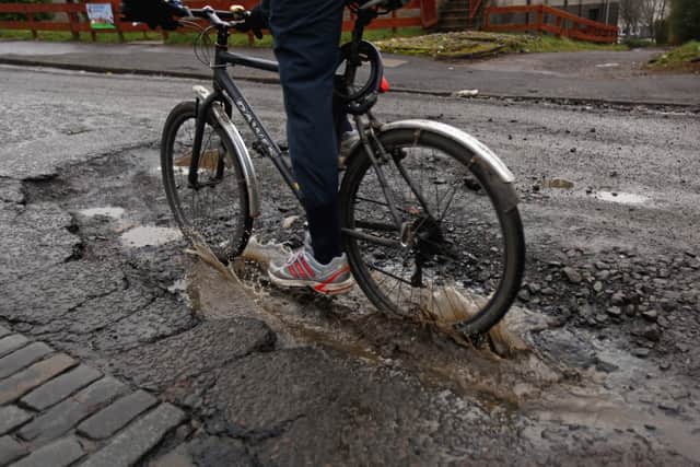 A cyclist rides through a pothole on March 4, 2011 in Glasgow, Scotland. The city’s roads had similar issues with potholes back in 2011 due to one of the coldest Winters on record