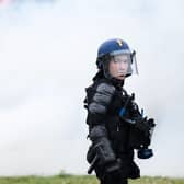 A French gendarme stands next to smoke during a demonstration as part of a national day of strikes and protests, a week after the French government pushed a pensions reform through parliament without a vote, using the article 49.3 of the constitution, in Nantes, western France, on March 23, 2023