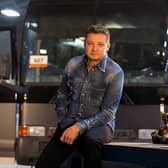 Jeremy Renner on set of Rennervations, a bus behind him and some power tools to one side (Credit: Disney+)