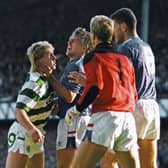 Celtic striker Frank McAvennie is held by the throat by Rangers defender Graham Roberts as goalkeeper Chris Woods and Terry Butcher (r) look on
