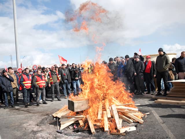 Striking employees gather around a fire outside Gronfreville-l'Orcher refinery on March 24, 2023