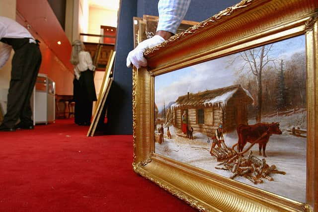 A member of staff at Lyon and Turnbull holds ‘Chopping logs outside a snow covered cabin'