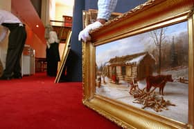 A member of staff at Lyon and Turnbull holds ‘Chopping logs outside a snow covered cabin'