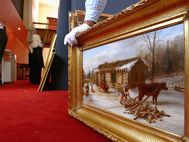 A member of staff at Lyon and Turnbull holds ‘Chopping logs outside a snow covered cabin'