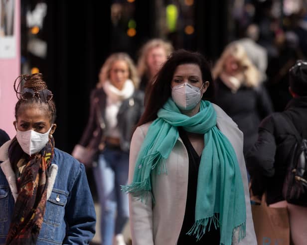 A woman wears a face mask while walking on Oxford Street.