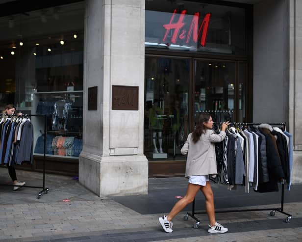 Retail workers move rails of clothes past a H&M store on Oxford Street.