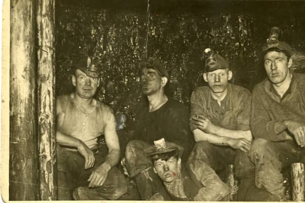 An unnamed group of Wishaw miners at the coalface, 1936. The miners along the back row are wearing caps with fittings for a carbide lamp. These were known locally as 'Yankee caps', either because they were similar to baseball caps or because they were of American manufacture. They were still in use until the 1950s, when they were replaced by helmets made from compressed pulp.