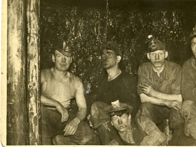 An unnamed group of Wishaw miners at the coalface, 1936. The miners along the back row are wearing caps with fittings for a carbide lamp. These were known locally as 'Yankee caps', either because they were similar to baseball caps or because they were of American manufacture. They were still in use until the 1950s, when they were replaced by helmets made from compressed pulp.