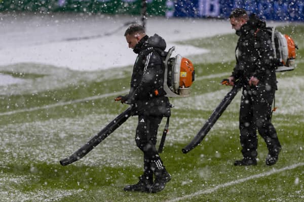Ground staff attempt to clear snow from the pitch at Celtic Park