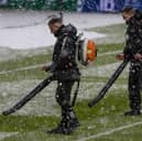 Ground staff attempt to clear snow from the pitch at Celtic Park