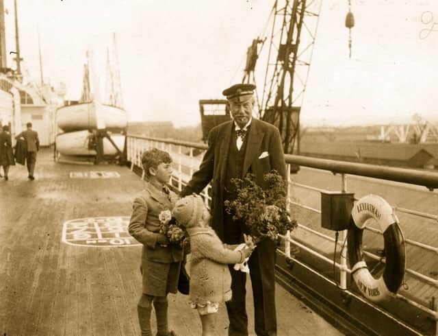 Scottish merchant, philanthropist and yachtsman Sir Thomas Lipton, is presented with flowers by his godson, Alfred Lipton Bowker, and June Lipton, on board the liner SS Leviathan before a trip to the USA, where he is to watch his yacht 'Shamrock V', competing in the America's Cup, 9th August 1930.