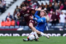 Alan Forrest of Heart of Midlothian is challenged by Ross McCausland of Rangers 