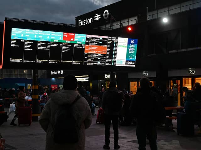 Rail travellers look at an electronic information board displaying train time information outside Euston Station in London. Photo: JUSTIN TALLIS/AFP via Getty Images