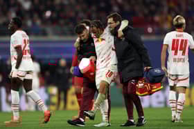 Xavi Simons of RB Leipzig leaves the pitch with medical staff after an injury against Liverpool 