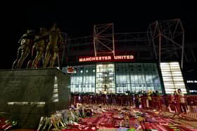 Tributes to former Manchester United player Denis Law surround the George Best, Denis Law and Sir Bobby Charlton statue outside of the stadium 
