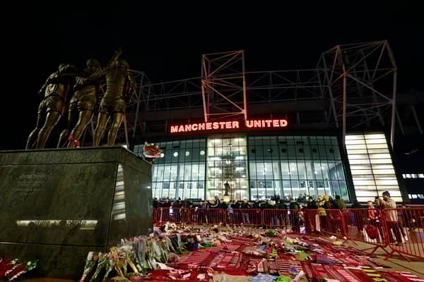 Tributes to former Manchester United player Denis Law surround the George Best, Denis Law and Sir Bobby Charlton statue outside of the stadium 