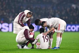 Bayern Munich's players and physio's comfort Bayern Munich defender Alphonso Davies after injuring his groin vs Feyenoord