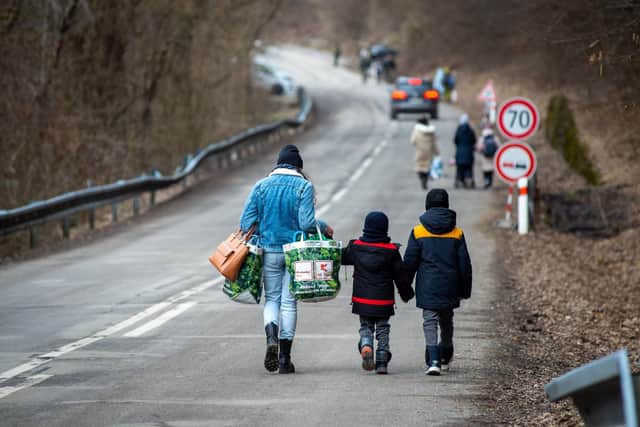 A woman with two children and carrying bags walk on a street to leave Ukraine after crossing the Slovak-Ukrainian border in Ubla, eastern Slovakia, close to the Ukrainian city of Welykyj Beresnyj, on February 25, 2022, following Russia's invasion of the Ukraine. Photo by PETER LAZAR/AFP via Getty Images