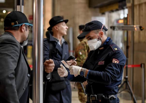 A police officer wearing a mask checks passengers leaving from Milan main train station, Italy, Could we end up in this situation?