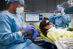 Dentist Fiez Mugha and Dental Nurse Johanna Bartha don their protective gloves and face shields at their dental practice. Photo by Leon Neal/Getty Images