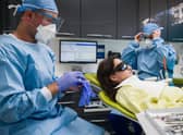 Dentist Fiez Mugha and Dental Nurse Johanna Bartha don their protective gloves and face shields at their dental practice. Photo by Leon Neal/Getty Images
