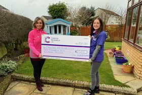 Gill is pictured handing over a cheque for £10,600 to Amanda Harris, from Cancer Research UK.