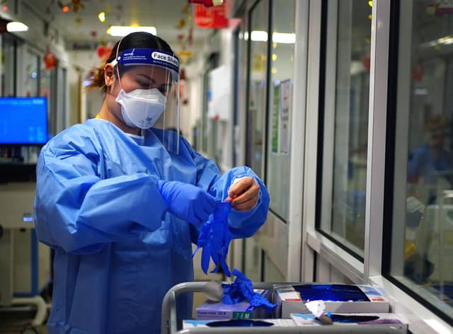 A nurse puts on PPE in a ward for Covid patients at King's College Hospital, in south east London. Picture date: Tuesday December 21, 2021.