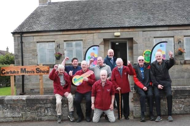 Carluke Men's Shed members celebrate after moving into their new premises in the town.