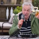 Larry Lamb battling the wind, delivering The Sipping Forecast to help the country navigate unpredictable pub-garden weather this spring.