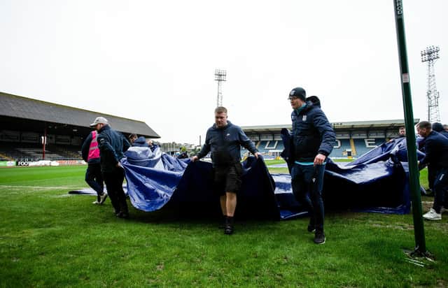 Dundee groundsmen remove the pitch covers ahead of the postponement of the match against Rangers. (Photo by Ewan Bootman / SNS Group)