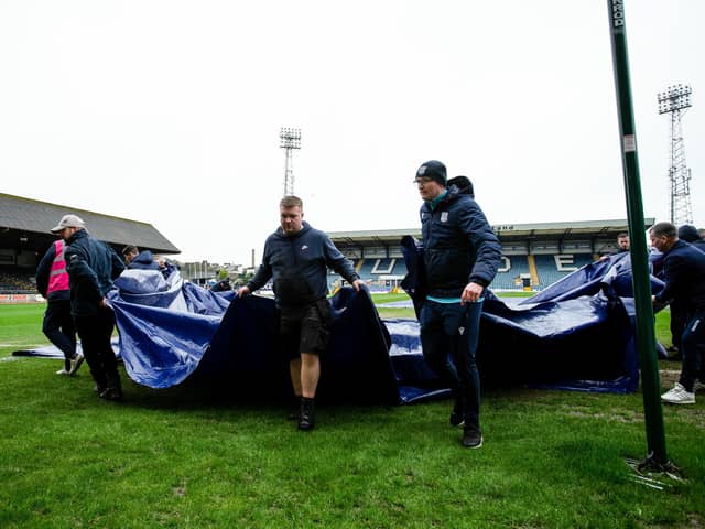 Dundee groundsmen remove the pitch covers ahead of the postponement of the match against Rangers. (Photo by Ewan Bootman / SNS Group)