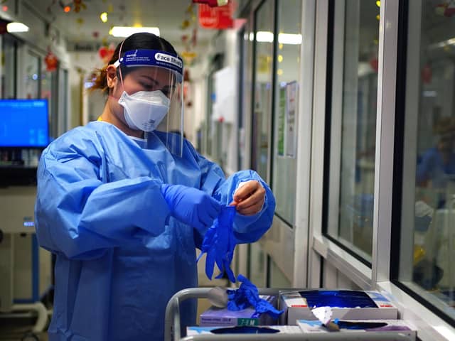 A nurse puts on PPE in a ward for Covid patients at King's College Hospital, in south east London. Picture date: Tuesday December 21, 2021.