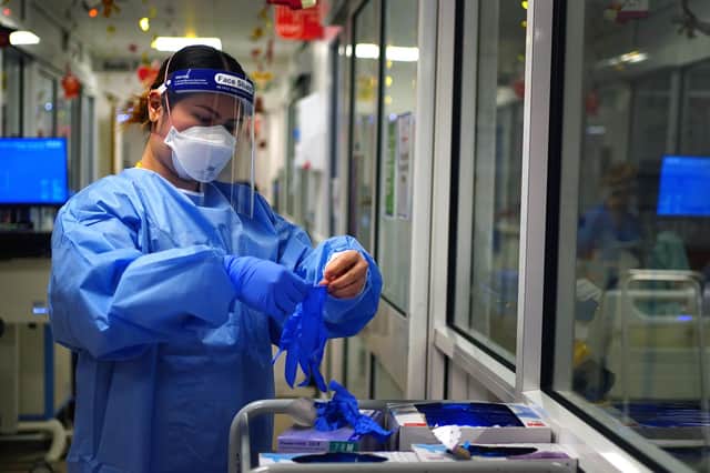A nurse puts on PPE in a ward for Covid patients at King's College Hospital, in south east London. Picture date: Tuesday December 21, 2021.
