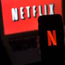 A computer screen and mobile phone display the Netflix logo. Photo by OLIVIER DOULIERY/AFP via Getty Images.